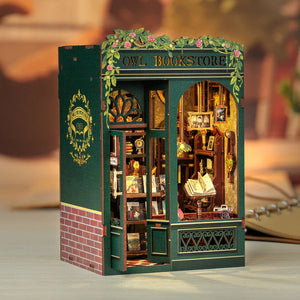 Front view of the assembled Owl Bookstore DIY kit with lush green accents and detailed miniature bookshelves.