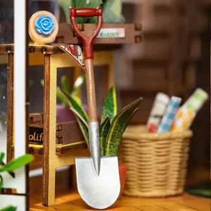 Detail shot of miniature gardening props: a large silver shovel, potted plants, and a woven basket.