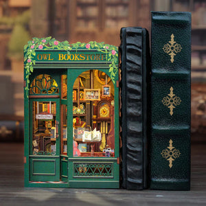 The Owl Bookstore book nook inserted between two large, leather-bound books on a bookshelf, showing its decorative use.